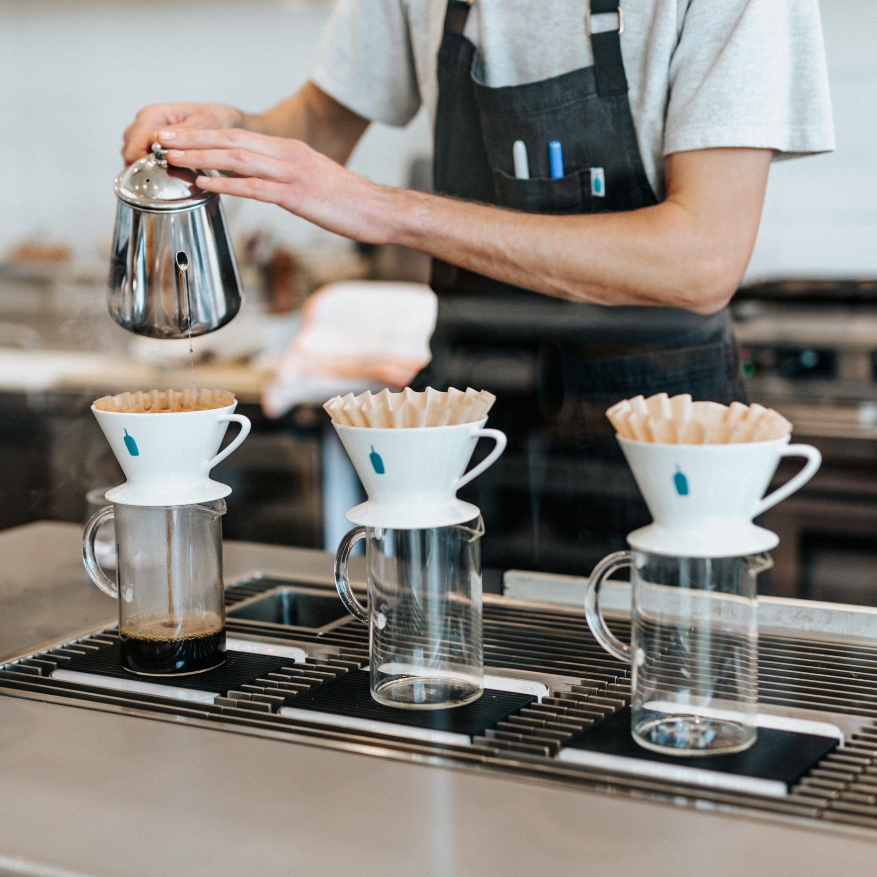 Barista at coffeeshop preparing pour over coffee.