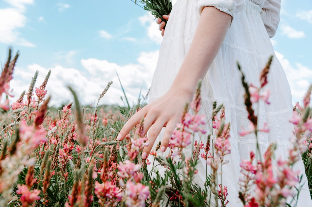 Close,Up,Hand,Of,Woman,In,White,Dress,Touching,Blossoming