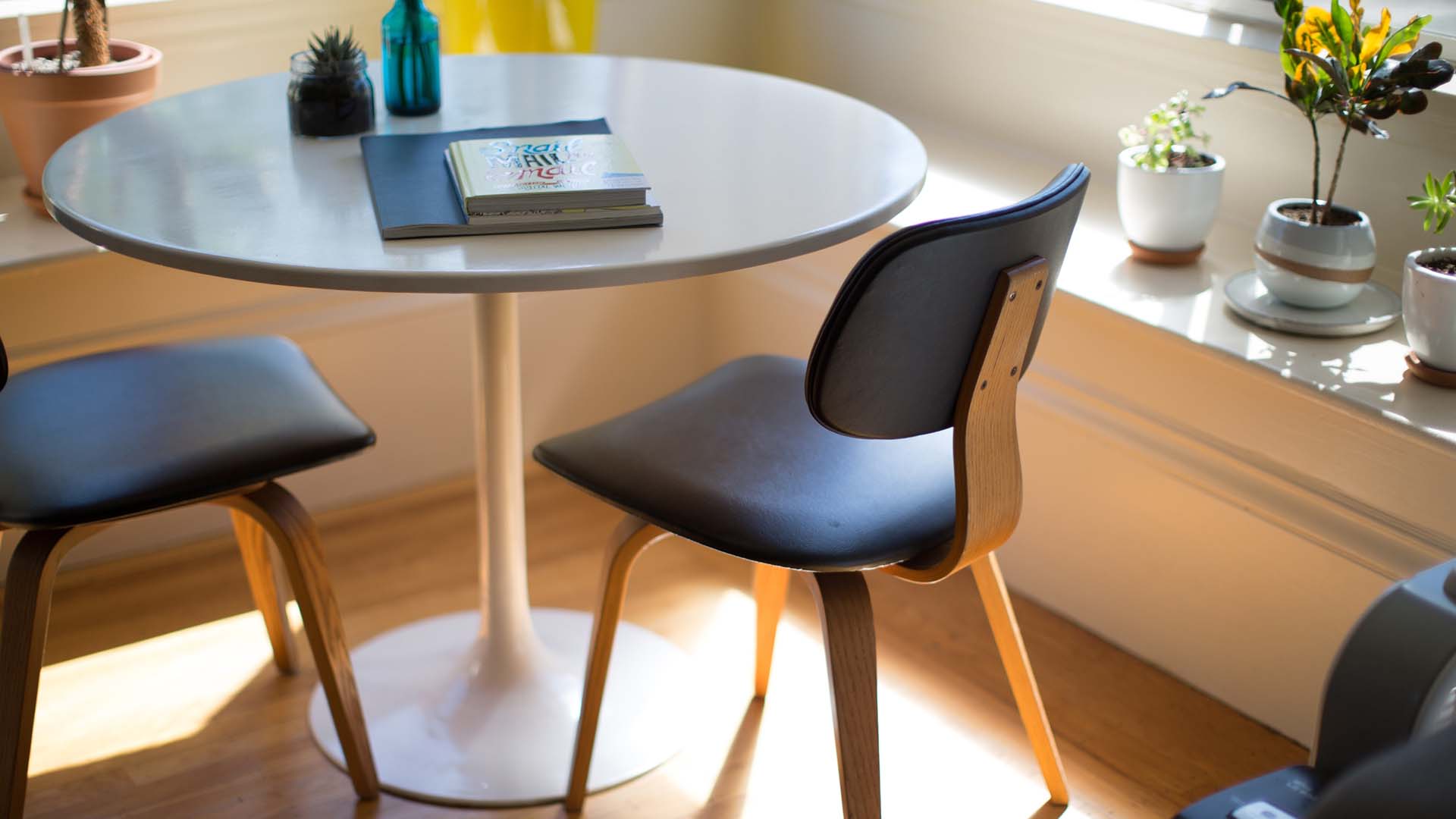 Dining room with bench seats, round table, modern dining table, and potted plants.