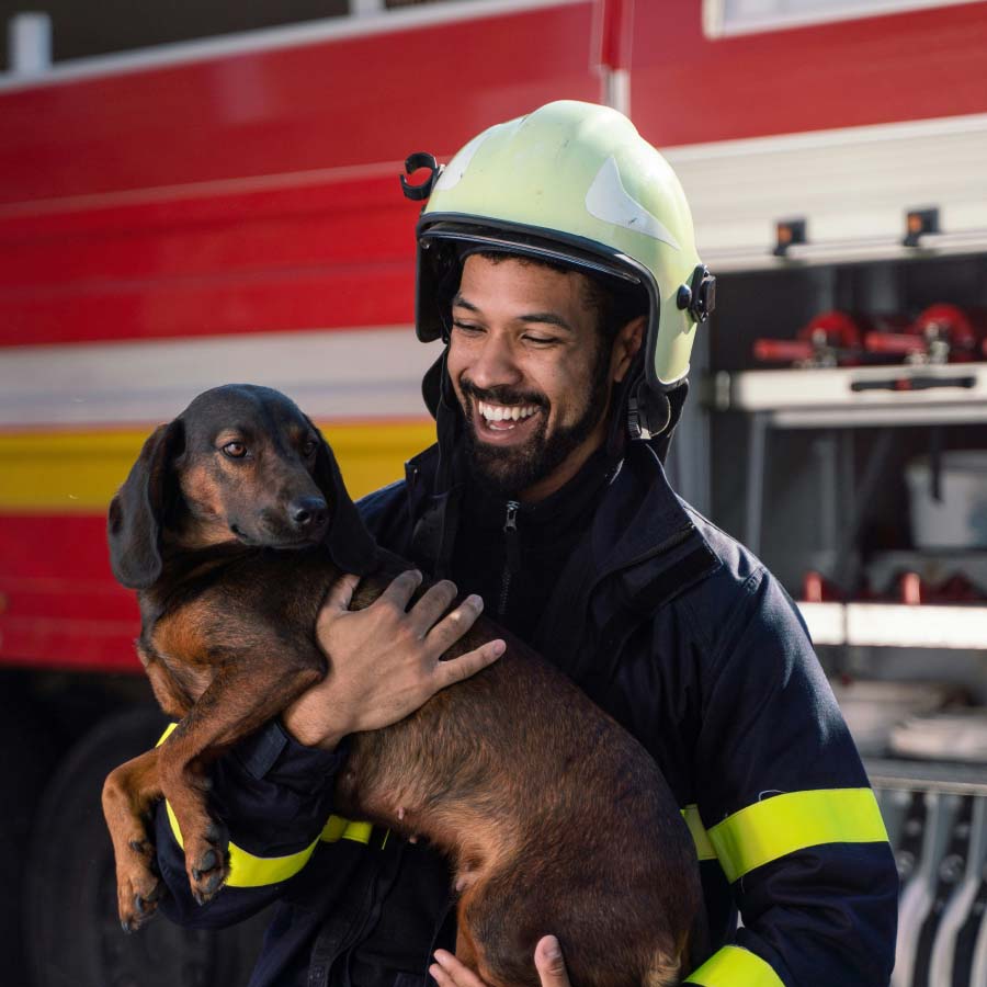 Firefighter wearing their equipment and holding dog.